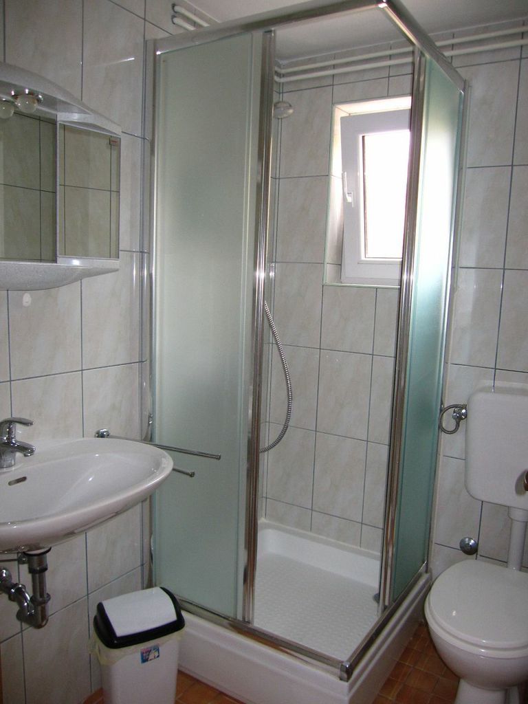 A bathroom with a glass-enclosed shower, a sink, and a toilet.