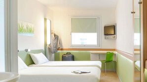 A hotel room with two beds, a desk, a chair, a suitcase, and a TV. - Ibis Budget Frankfurt Offenbach Sued (Offenbach am Main)