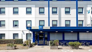 A modern hotel building with a blue and white facade, multiple windows, and a sign indicating it is a budget hotel. - Ibis Budget Frankfurt Offenbach Sued (Offenbach am Main)