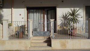 A residential building with a front entrance, a staircase leading to the door, and a metal railing around the entrance area. - Loft a few steps from the sea (Pozzallo)