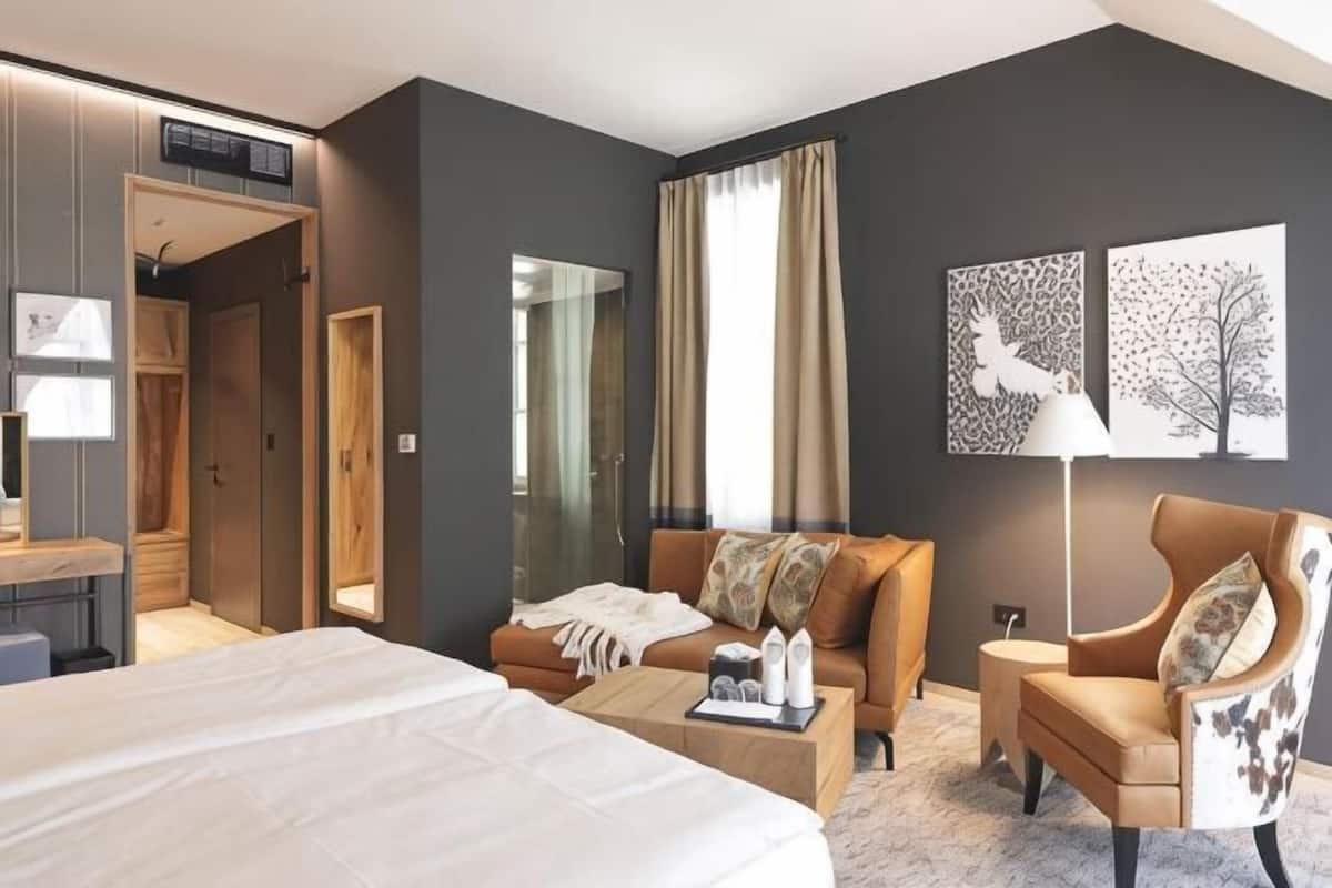 Une chambre d’hôtel comprenant un lit, un canapé, une chaise, un bureau et un miroir.