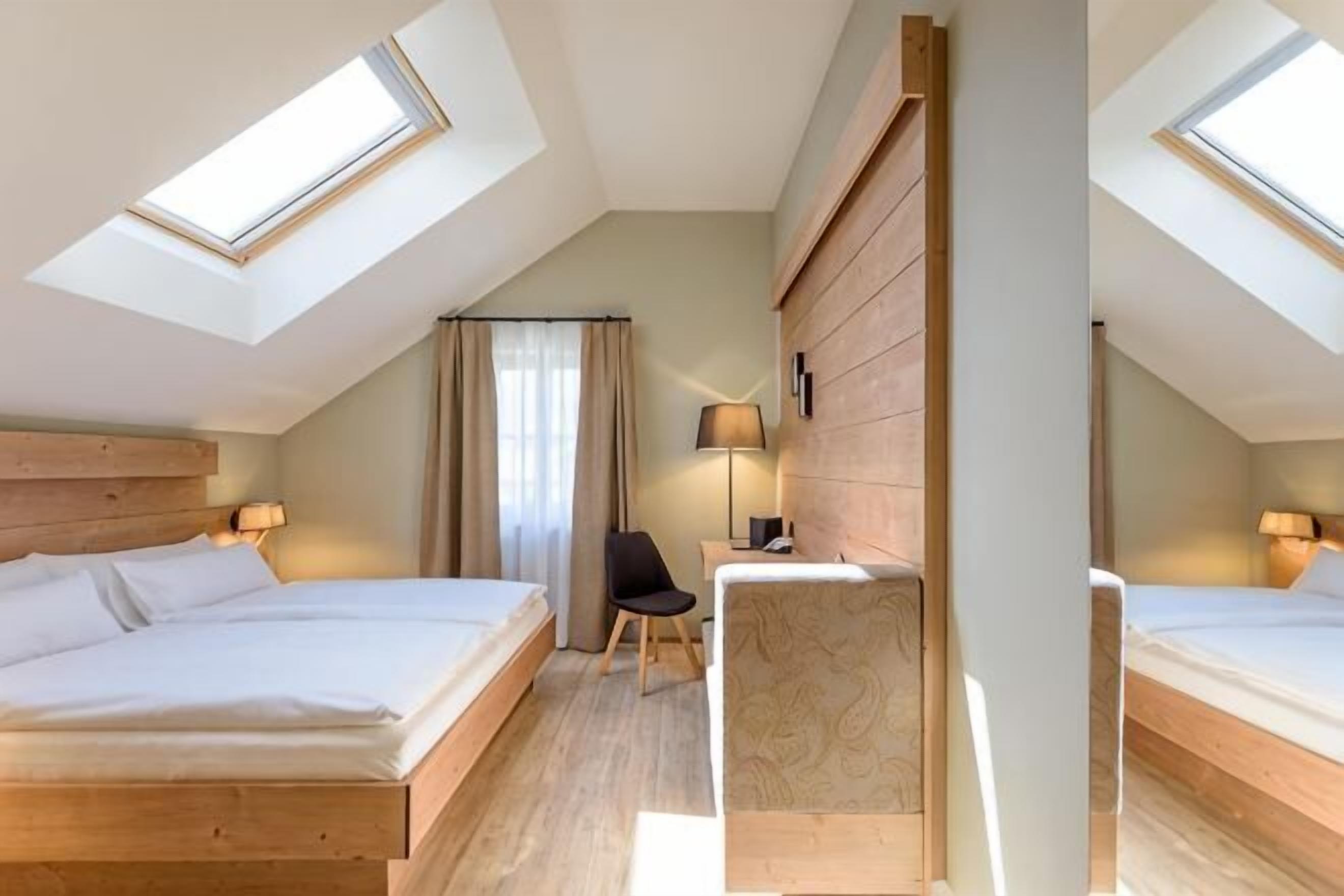 A bedroom with two beds, a desk, a chair, and a window.