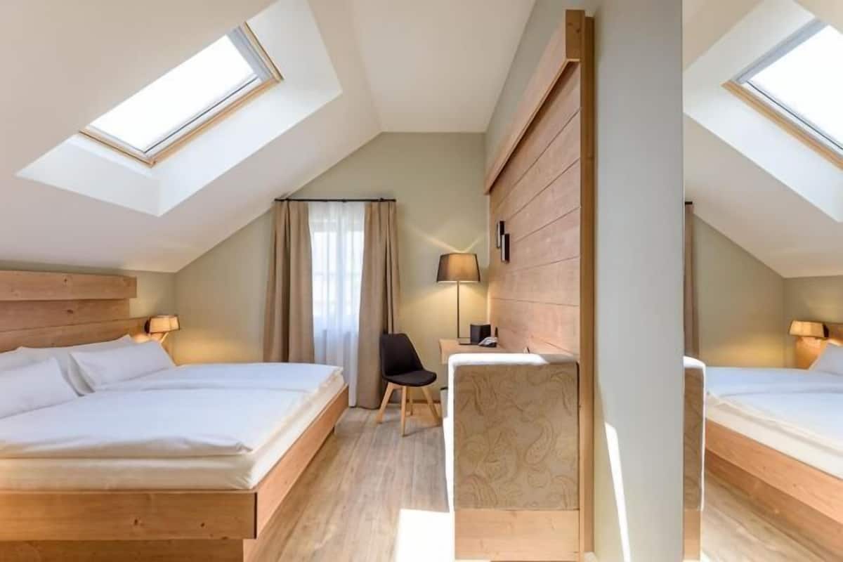 Une chambre avec deux lits, un bureau, une chaise et une fenĂŞtre.