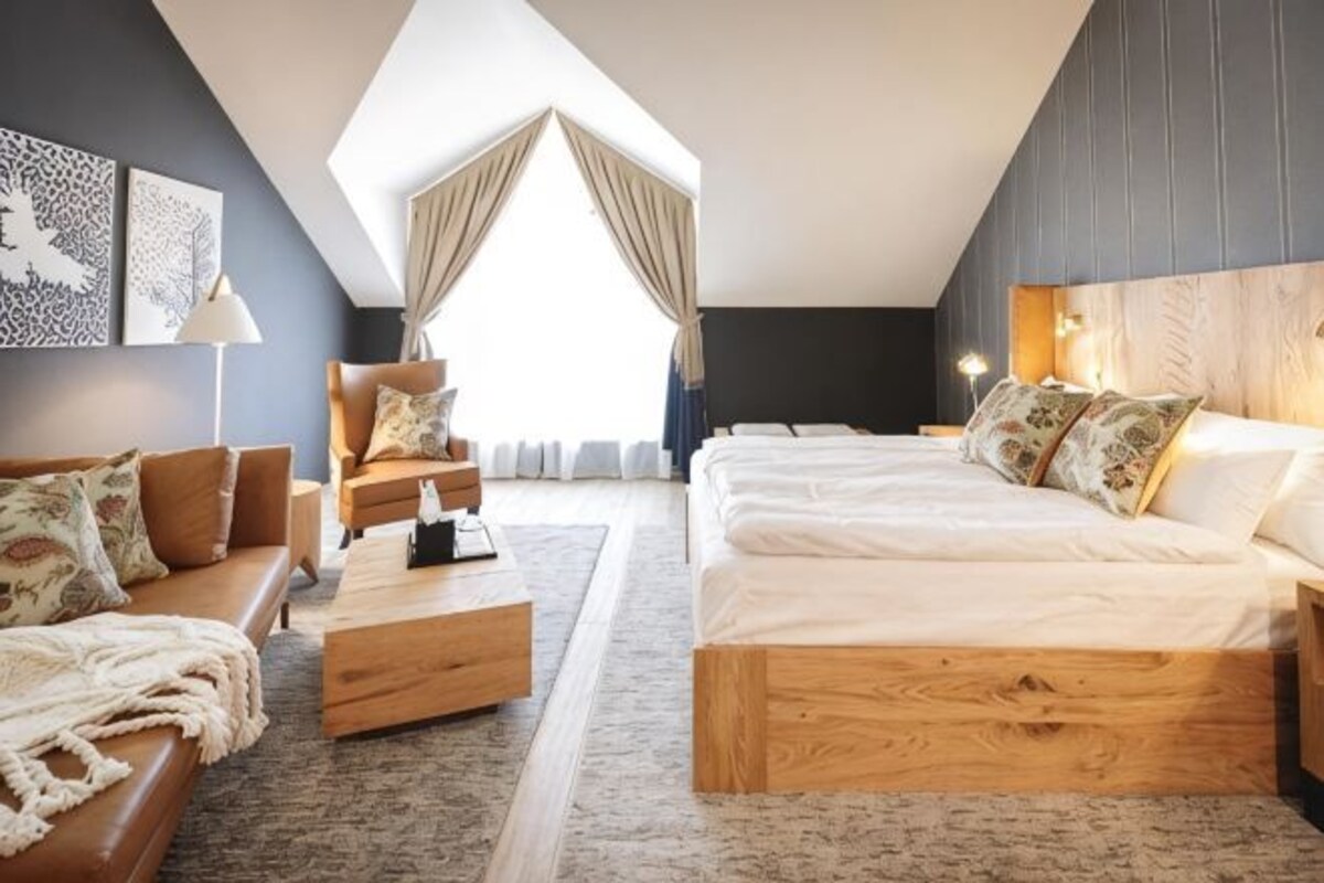 Una habitación de hotel moderna con una cama grande, un sofá, una mesa de centro y un escritorio.