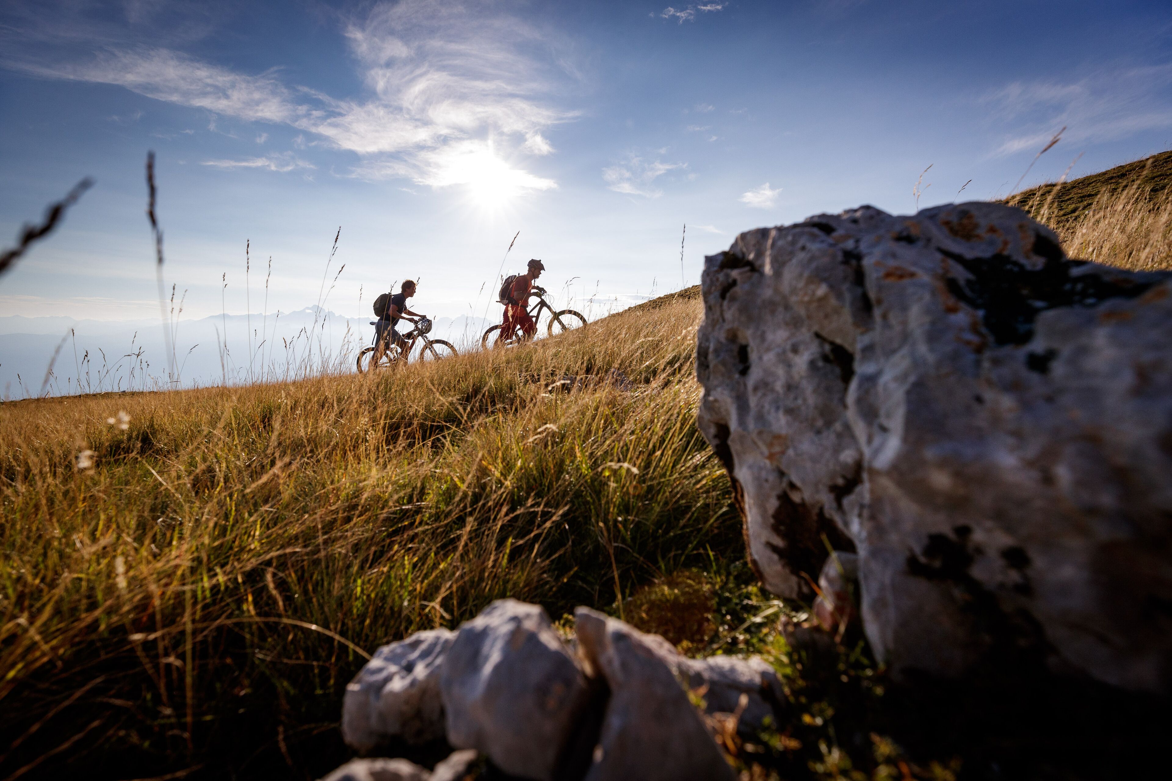 Un paisaje rocoso con dos ciclistas en un sendero.