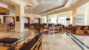 A spacious lobby with a central seating area, a reception desk, and large windows providing natural light.