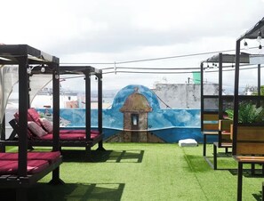 A rooftop terrace with artificial grass, a mural, and seating areas.