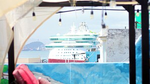 A view from inside a tent with a red cushioned seat facing a large cruise ship.