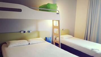A hotel room with two beds, a green bag on the top bunk, and a blue pillow on the lower bed.