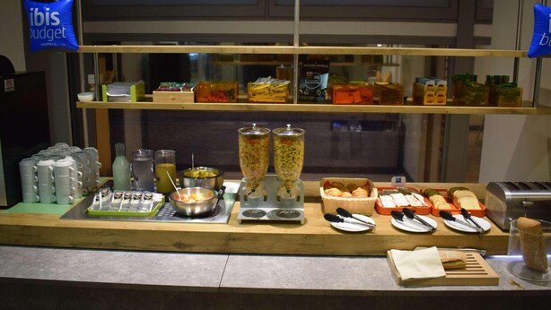 Una mesa de buffet con diferentes alimentos, utensilios y recipientes.