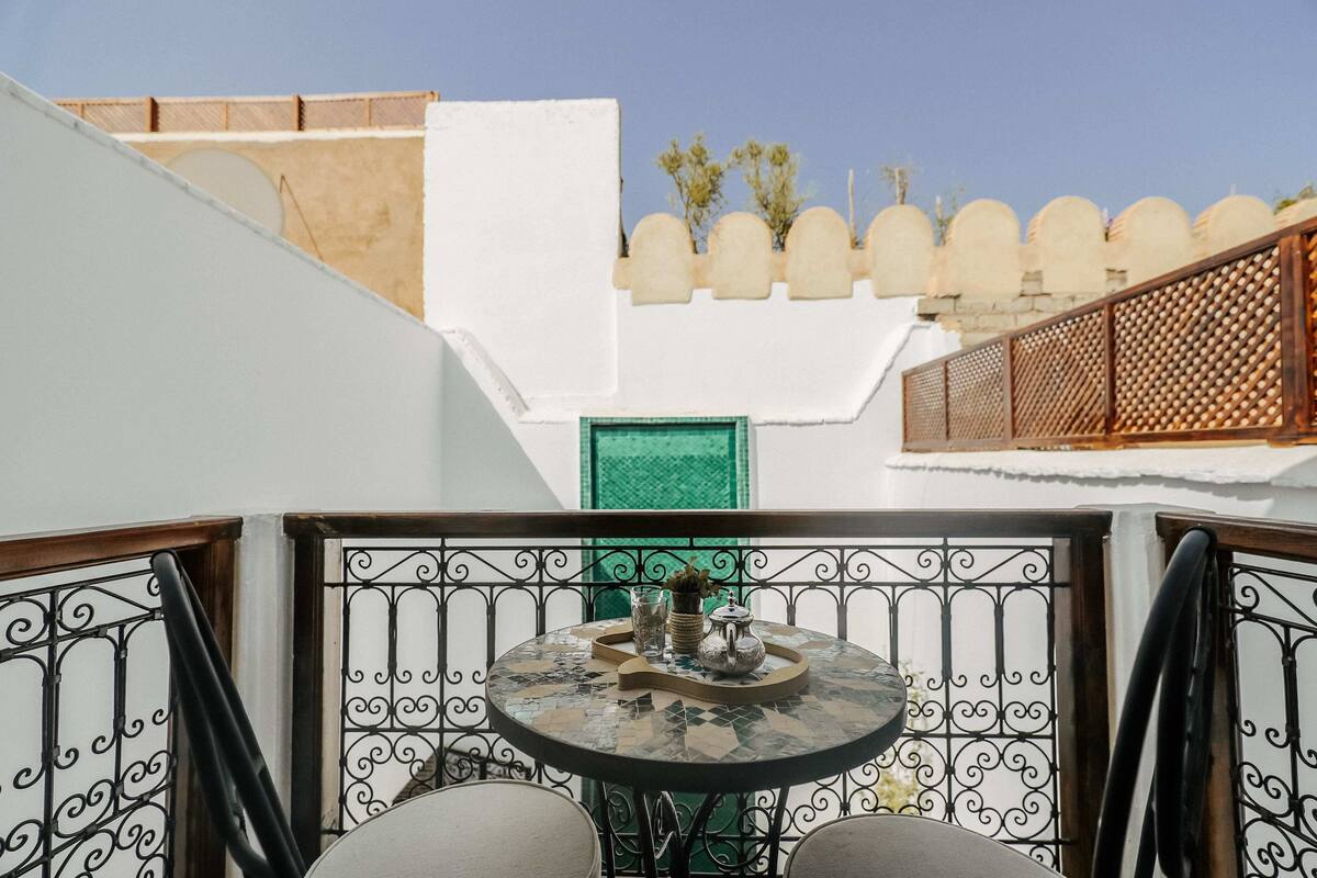 A balcony with a round table, chairs, and decorative items.