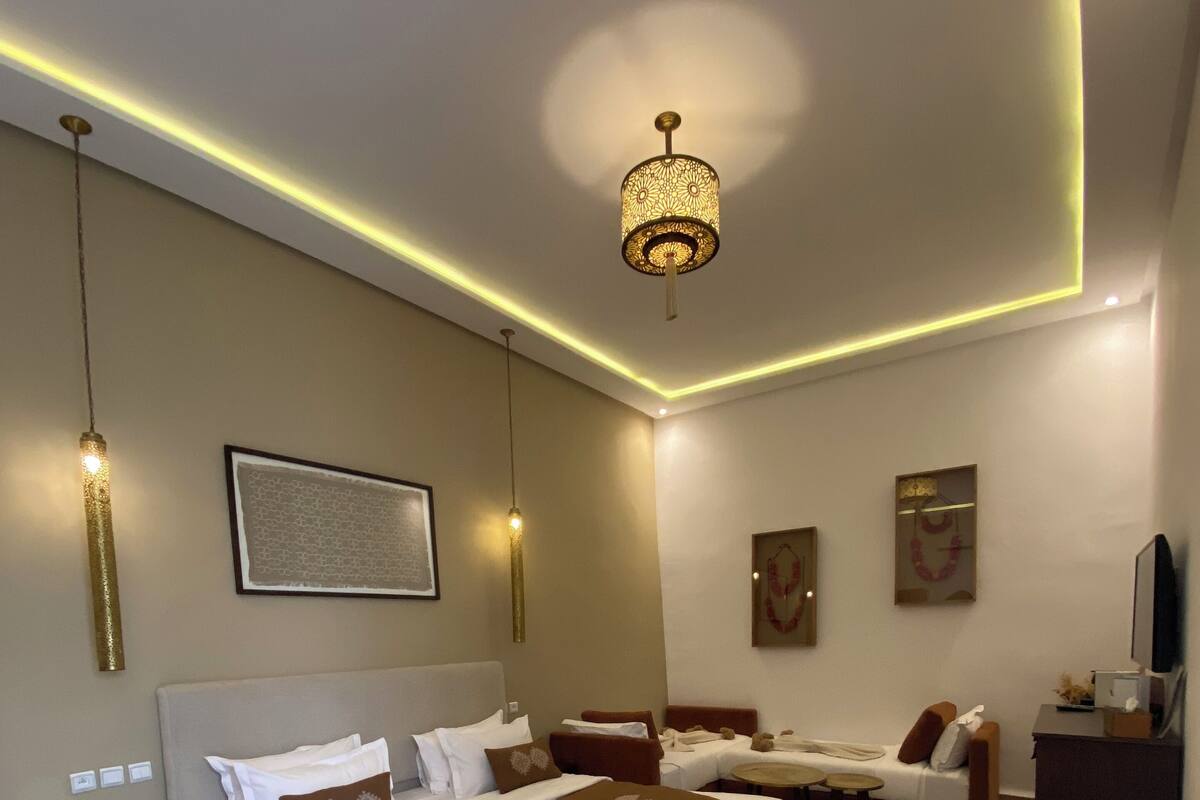 A modern bedroom with a large bed, bedside tables, a desk, and a chandelier.