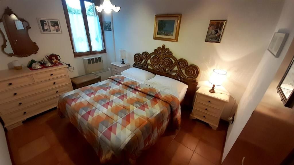 Ein Schlafzimmer mit einem Bett, Nachttischen, einer Kommode und einem Fenster.