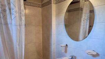 Un bagno con un lavabo su piedistallo, uno specchio e una tenda da doccia.