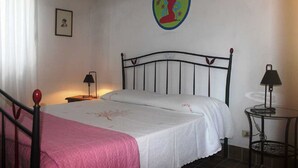 A bedroom with a bed, two bedside tables, a small round table, and a wall decoration.