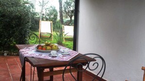 A patio table with a fruit plate, cups, and a chair.