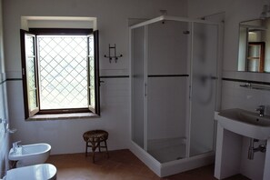 Ein Badezimmer mit Dusche, Waschbecken, Toilette und einem Fenster mit Blick.