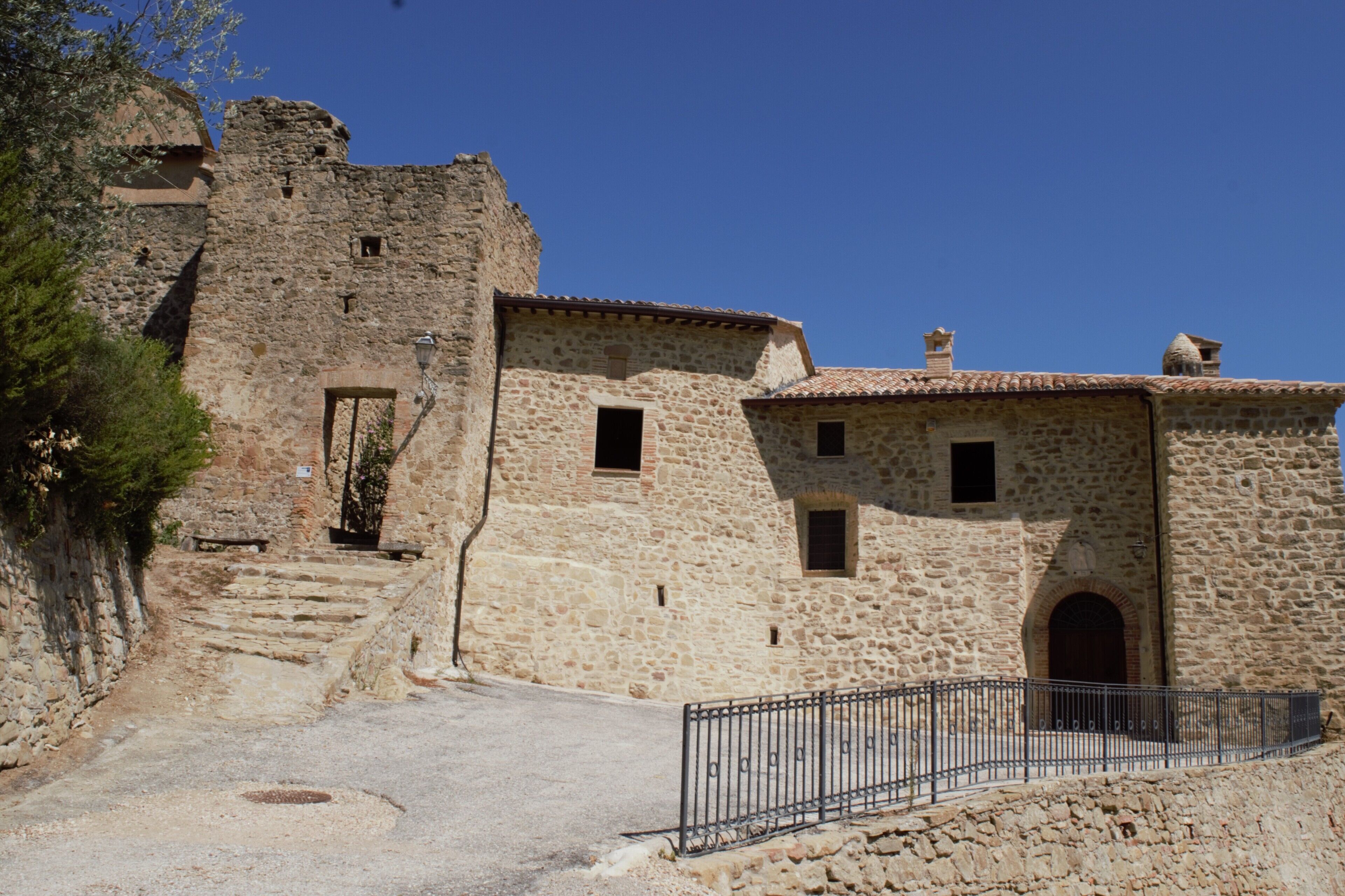 A stone building with a rustic appearance, featuring a small door and windows, and a paved pathway leading to it.