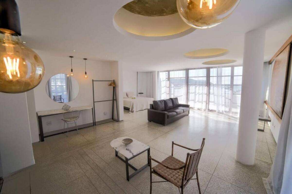 A spacious living area with a modern design, featuring a sofa, a dining table, and a coffee table.