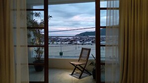 Un balcón con una silla, una planta en maceta y vistas a un puerto deportivo con barcos.