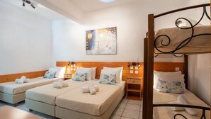A hotel room with two single beds, a bunk bed, a wooden headboard, a bedside table, and a wall-mounted artwork. - Family Room (4-5 Adults) - Semi Basement, near Center, Parikia (Paros Greece)