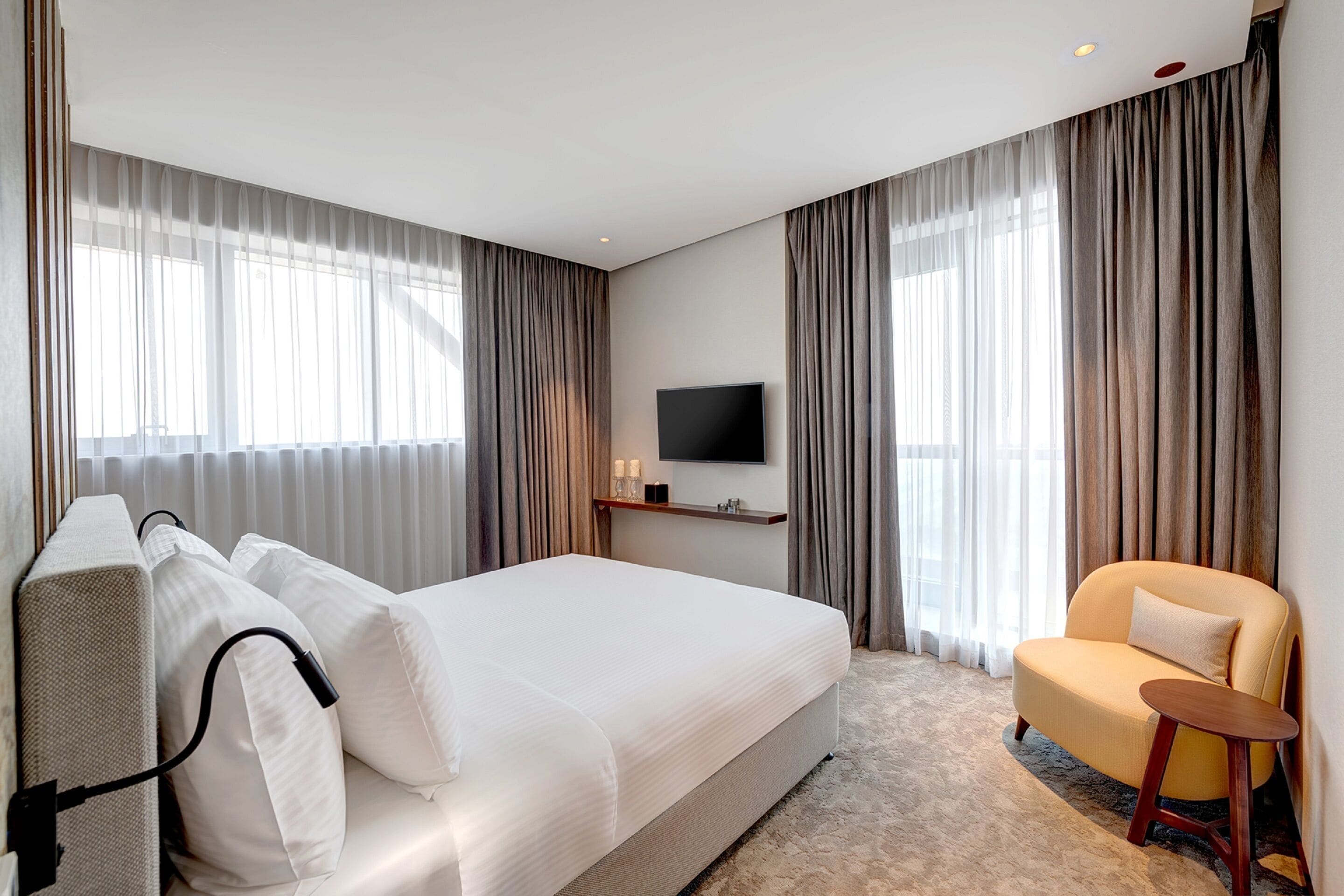 Une chambre d’hôtel avec un grand lit, un téléviseur fixé au mur, une table de chevet et une chaise.