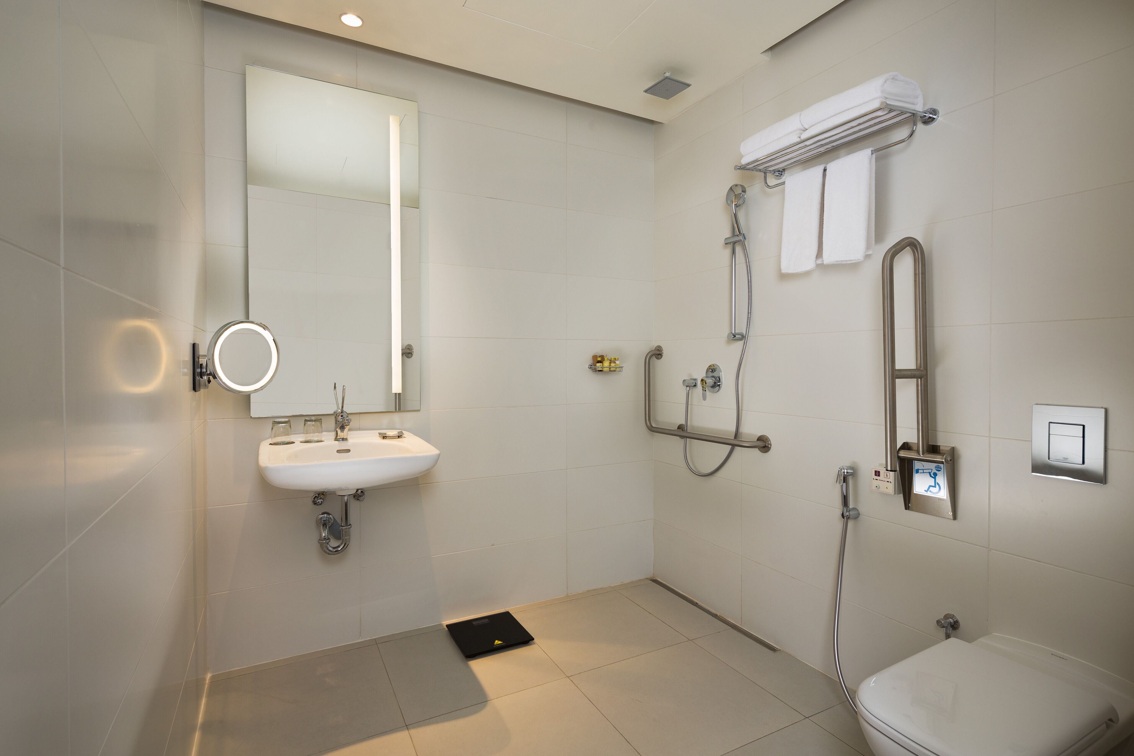 A modern bathroom with a sink, mirror, toilet, and shower.