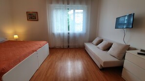 A bedroom with a bed, a sofa, a TV, and a lamp. - Affittacamere Residenza Chiara (Forlì)