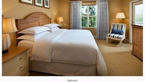 Un dormitorio con una cama grande, lámparas de noche, una silla y un aparador.