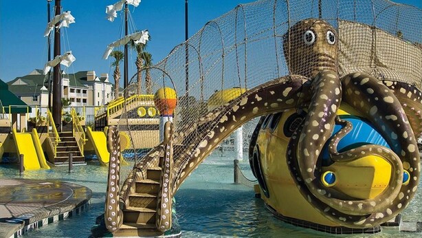 Un espace de jeux aquatiques sur le thème des poulpes, avec des toboggans et une zone délimitée par un filet.