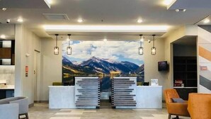 Una moderna zona de recepción con un mural de vistas a la montaña, un mostrador de recepción y asientos.