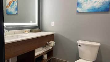 A bathroom with a modern vanity, a toilet, and two artworks on the walls.