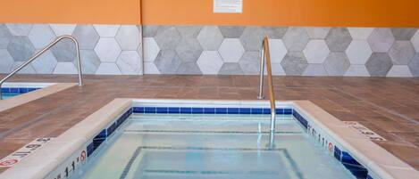 Una piscina con un diseño de baldosas hexagonales en las paredes, una escalera metálica y un cartel con normas.