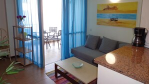 A living room with a sofa, coffee maker, and a painting on the wall.