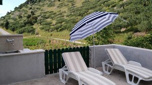 A patio with two white sun loungers and a striped umbrella. - Lovrečina sand beach (Postira)