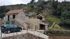 A stone house with a tiled roof, a car parked in front, and a mountainous backdrop. - Lovrečina sand beach (Postira)