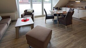 Un salon moderne avec un coin repas, un canapé, une table basse et une cuisine en arrière-plan.
