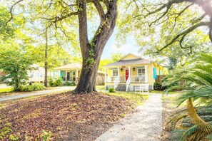 A yellow house with a porch, surrounded by trees and a pathway. - Walk to Beach!  Game Room!  Pets!  Screened porch! (Gulfport)