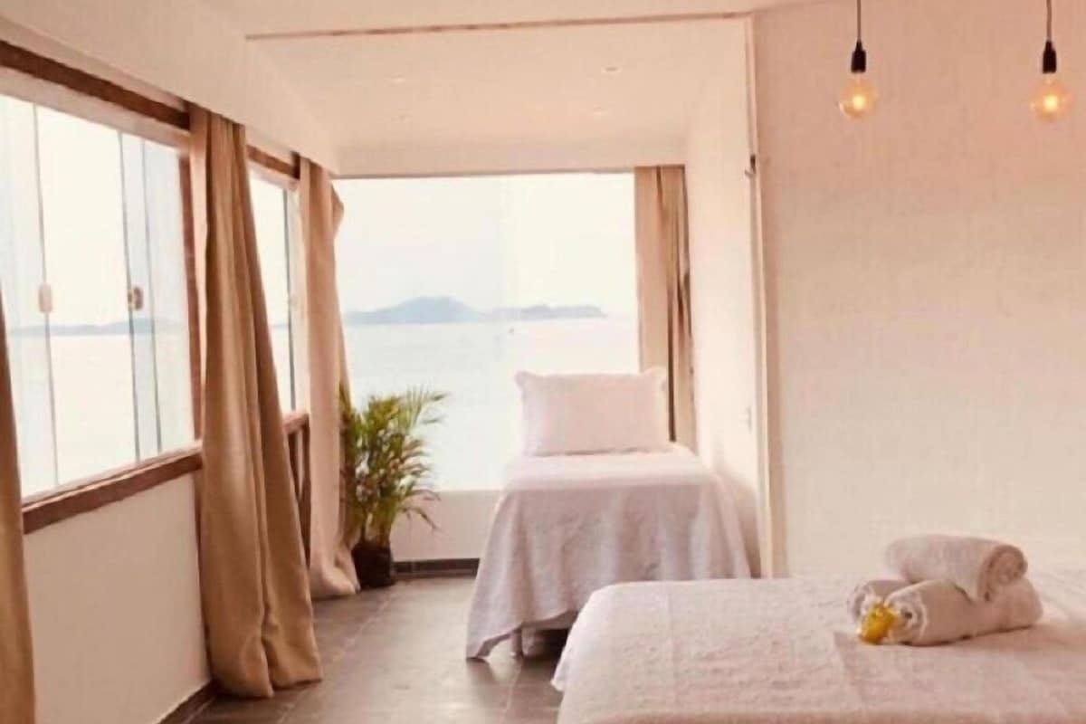 Ett hotellrum med två sängar, havsutsikt och en krukväxt.