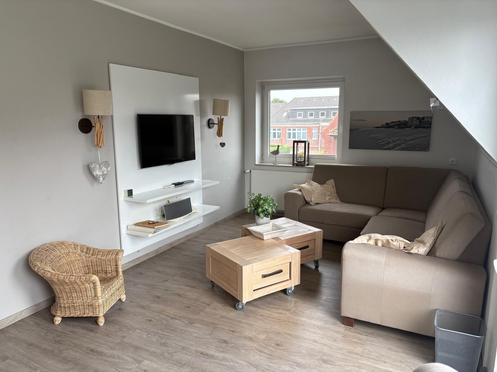 A modern living room with a flat-screen TV, a sofa, a coffee table, and a wicker chair.