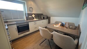 Eine moderne Küche mit Essbereich, Holzboden und einer Uhr an der Wand.
