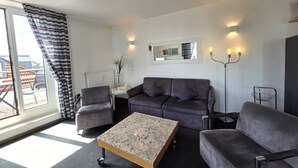 A modern living room with a sofa, two armchairs, a coffee table, a floor lamp, and a large window with curtains. - Duhner Düne apartment 25, WLAN, elevator, roof terrace, close to the beach, non-smoking (Cuxhaven)