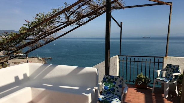 Ein Balkon mit weißer Möbel, Blick auf das Meer und ein Schiff in der Ferne.