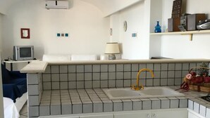 Eine kleine Küche mit Spüle, weißen Schränken und einer gefliesten Rückwand.