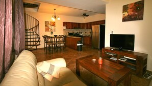 A living room with a sofa, coffee table, TV, and a kitchen area with a dining table and chairs. - Beautiful Two Bedroom In Gated Community SPECIAL RATES FOR MONTHLY! (El Pajonal)