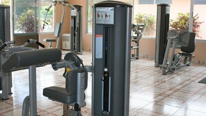 A gym with exercise machines, including a chest press and a leg press, with instructional posters on the wall. - Beautiful Two Bedroom In Gated Community SPECIAL RATES FOR MONTHLY! (El Pajonal)