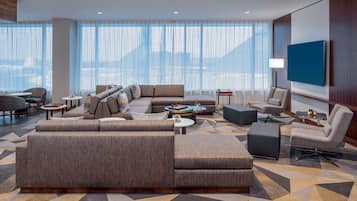 A modern living room with a large sectional sofa, a coffee table, and a TV mounted on the wall.