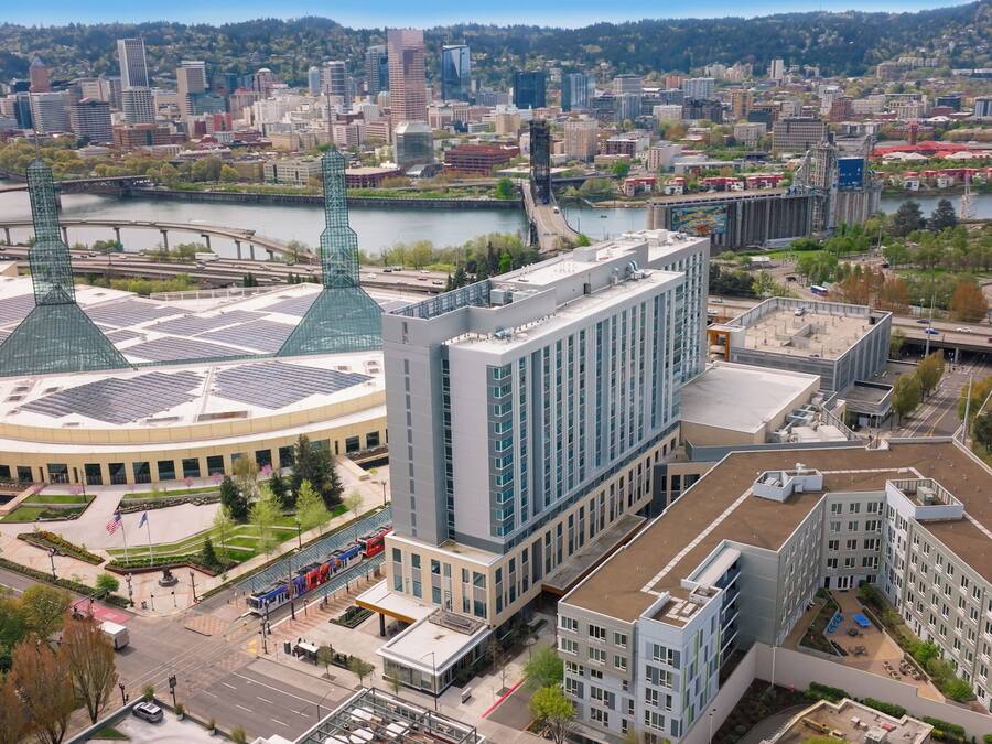 Un edificio moderno con fachada de vidrio central y una estructura circular con techo verde.
