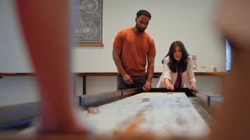 Two people at a table with a map, a window with a view, and a bicycle in the background.