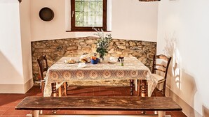 A stone-walled dining area with a table set for two, featuring a lace tablecloth and a rustic wooden bench. - Podere Piaggette of segalgari - Sea side  (castagneto carducci)